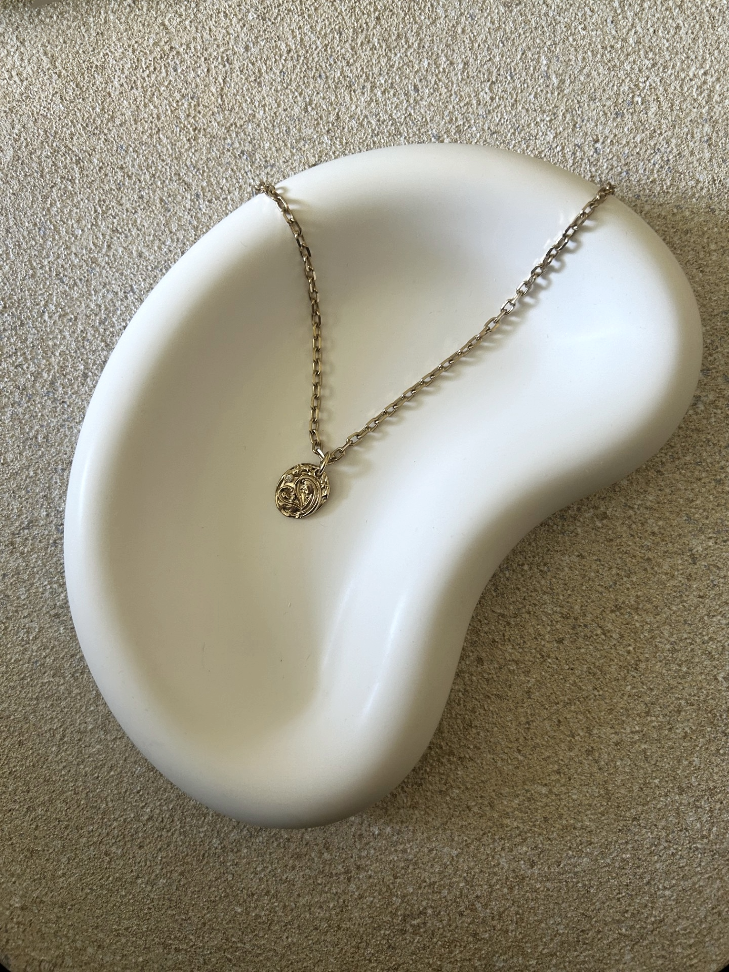 Handmade Home Accessories - A birds eye view photo of a chunky white curved jelly bean like trinket tray with a gold necklace styled on it.