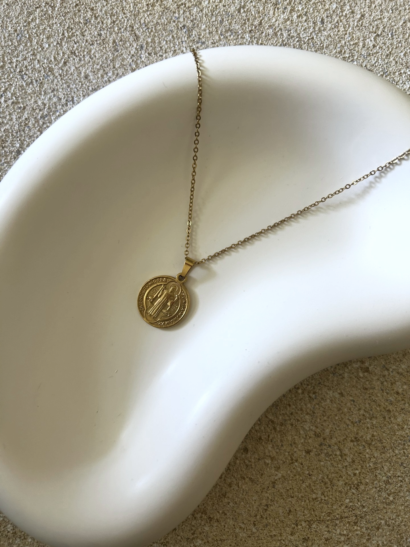 Handmade Home Accessories - a close up shot of a white trinket tray that is shaped like a jelly bean, it displays a coin style gold necklace.