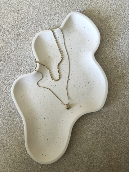 Handmade Home Accessories - birds eye view photo of a wiggly trinket tray thats cream with black dots on, displaying a two tier necklace