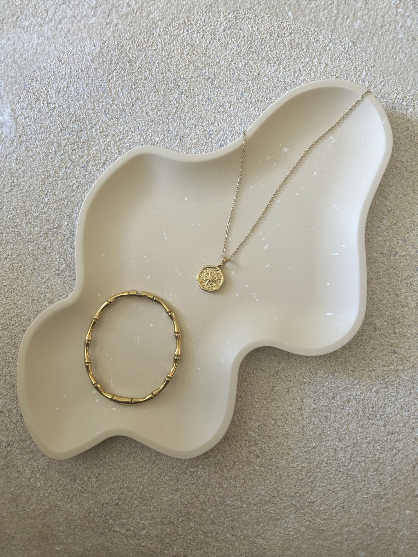 Handmade Home Accessories - a birds eye view shot of a brown trinket tray in a wiggle style with white splatters, displaying a gold necklace and bracelet