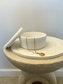 Handmade Home Accessories - a white textured pot, with the lid resting against the side and a gold coin necklace draping over the edge