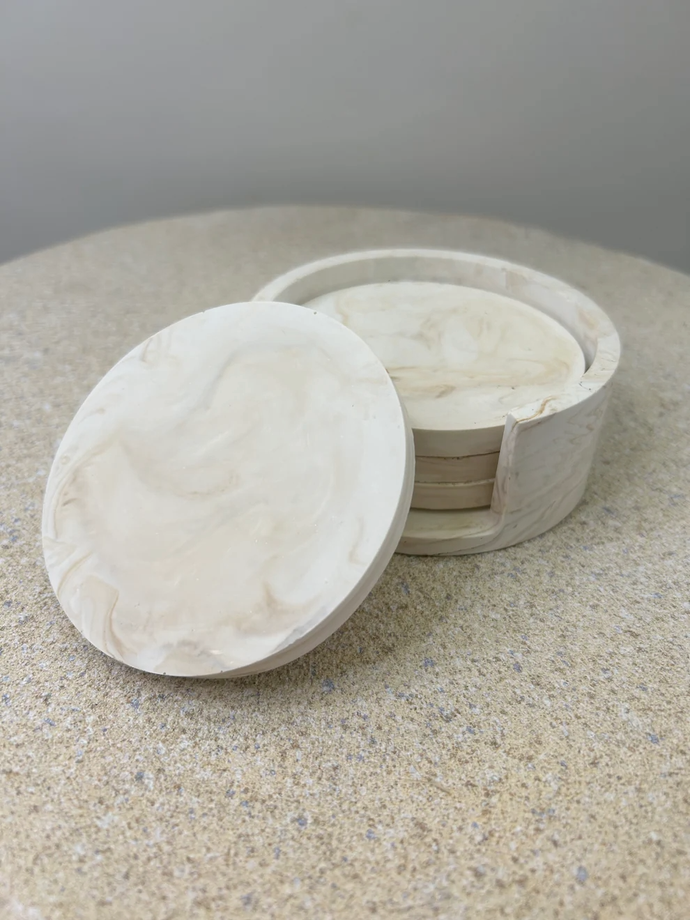 Handmade Home Accessories - A picture of a stack of four coasters in a holder with a coaster leaning on the front in beige marble