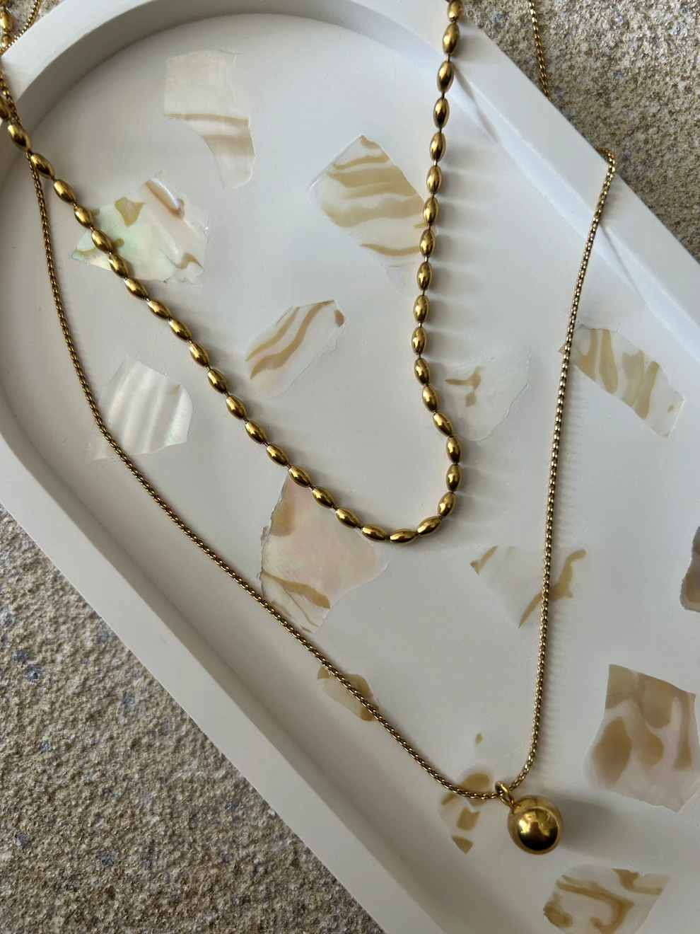 Handmade Home Accessories - A close up shot of a white oval trinket tray with abalone shell details with a two tier necklace on.