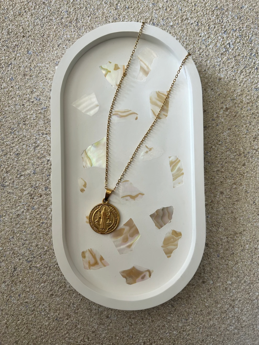 Handmade Home Accessories - A vertical shot of a white oval trinket tray with abalone shell details, with a gold coin necklace on the top.