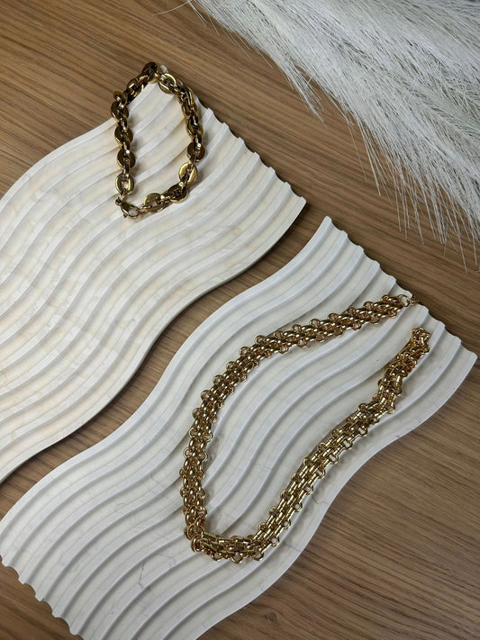 Two curved ripple trays styled with chunky gold jewellery – handcrafted sculptural accessories for a calming, tactile display.