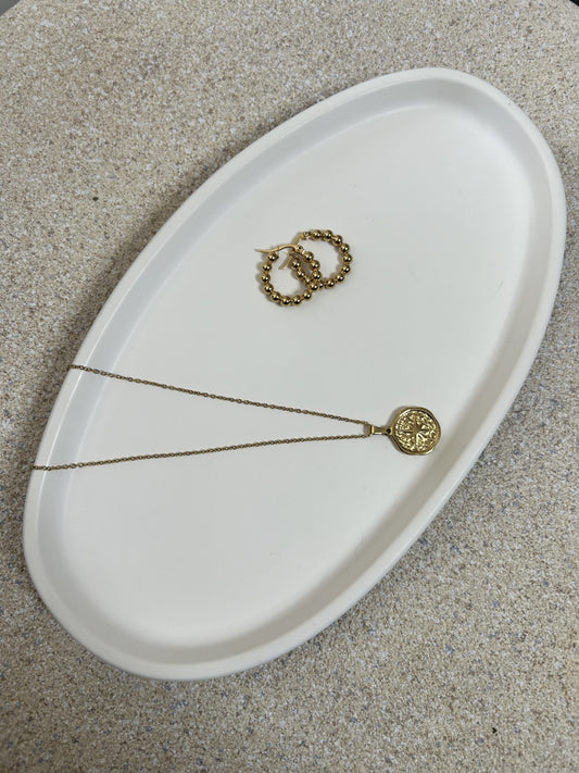 Handmade home accessories - pure white curve style trinket tray at a 45 degree angle being using to store gold jewellery on a stone textured surface.