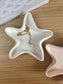 White star-shaped ceramic trinket dish styled with a delicate gold necklace and shell pendant, placed on a wooden surface for a natural, minimal aesthetic.