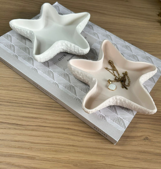 Pair of white and peach star-shaped trinket dishes displayed on a patterned box, each styled with gold jewellery to highlight their use as elegant, handmade home accessories.