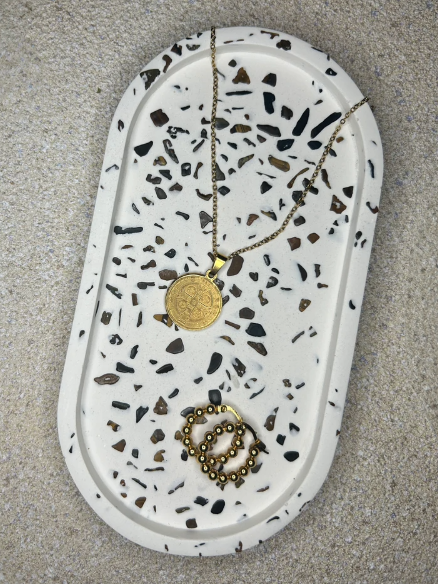 Handmade Home Accessories - Tiger's Eye gemstone trinket tray adorned with a gold coin necklace and a pair of gold hoop earrings on a natural stone background.