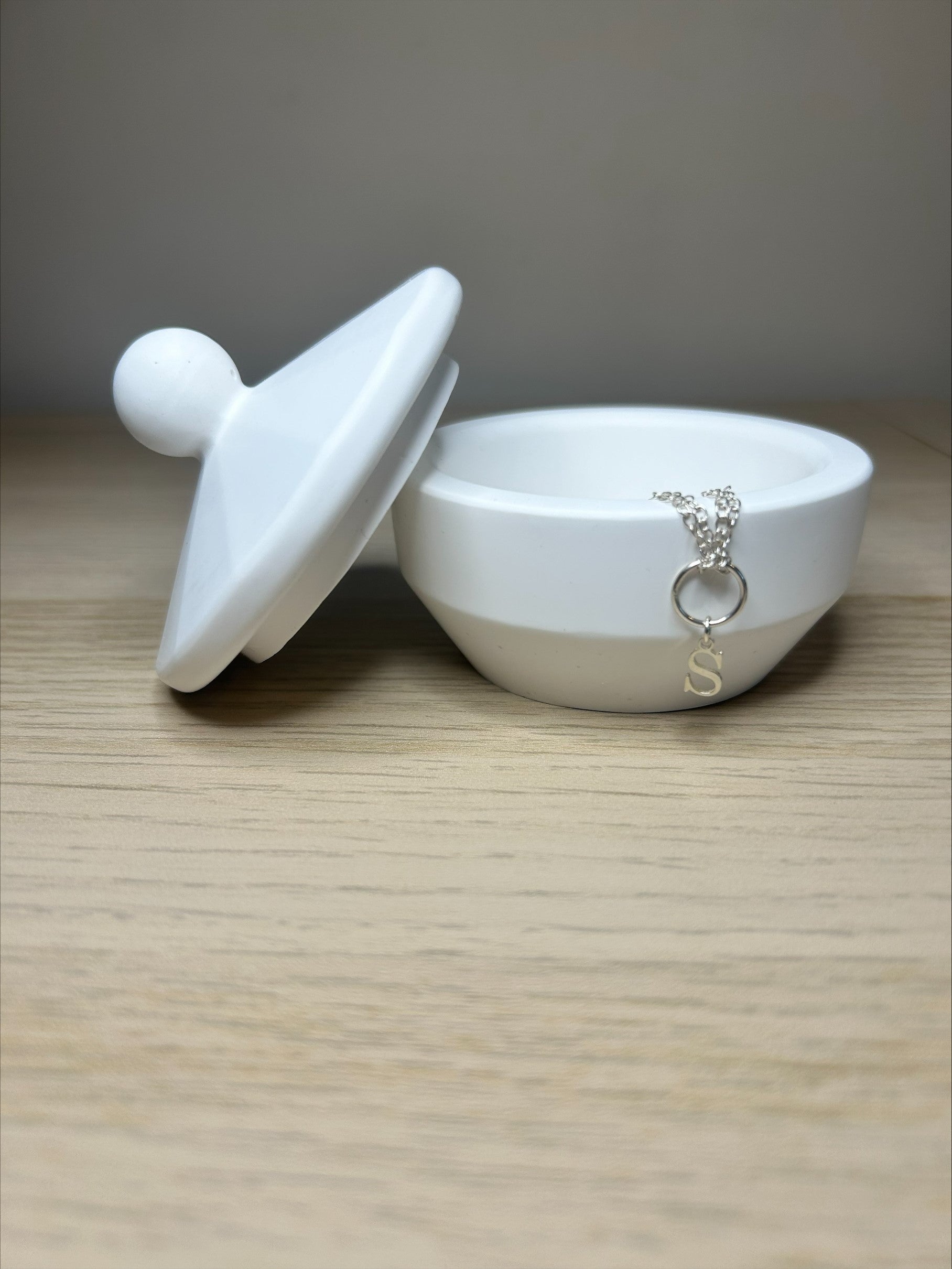 Handmade Home Accessories - a white trinket pot on a wooden background with a silver s initial necklace draped over the side