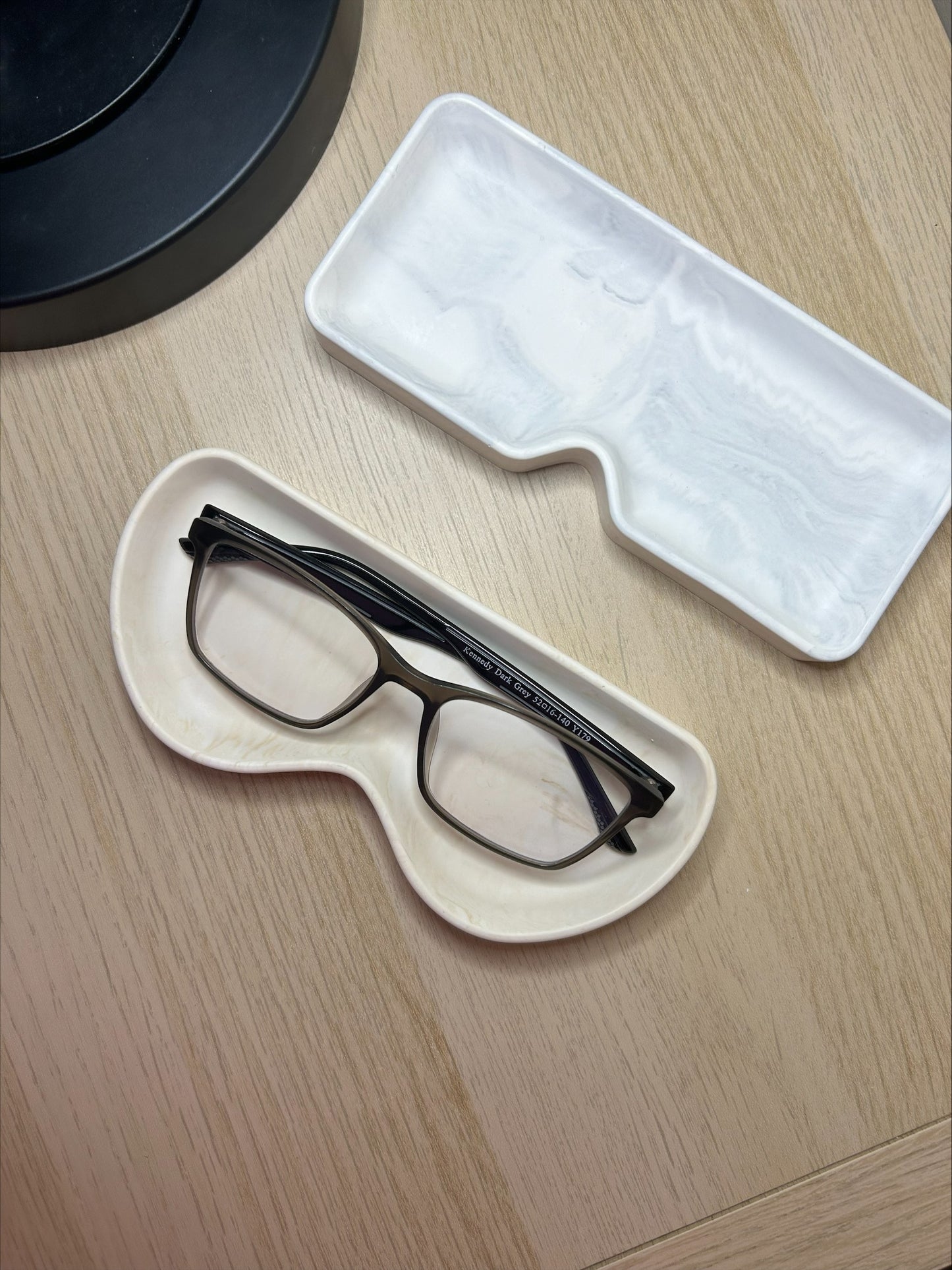 Handmade Home Accessories - two glasses trays, one empty square grey marble tray and one round beige marble tray with a pair of black reading glasses in.