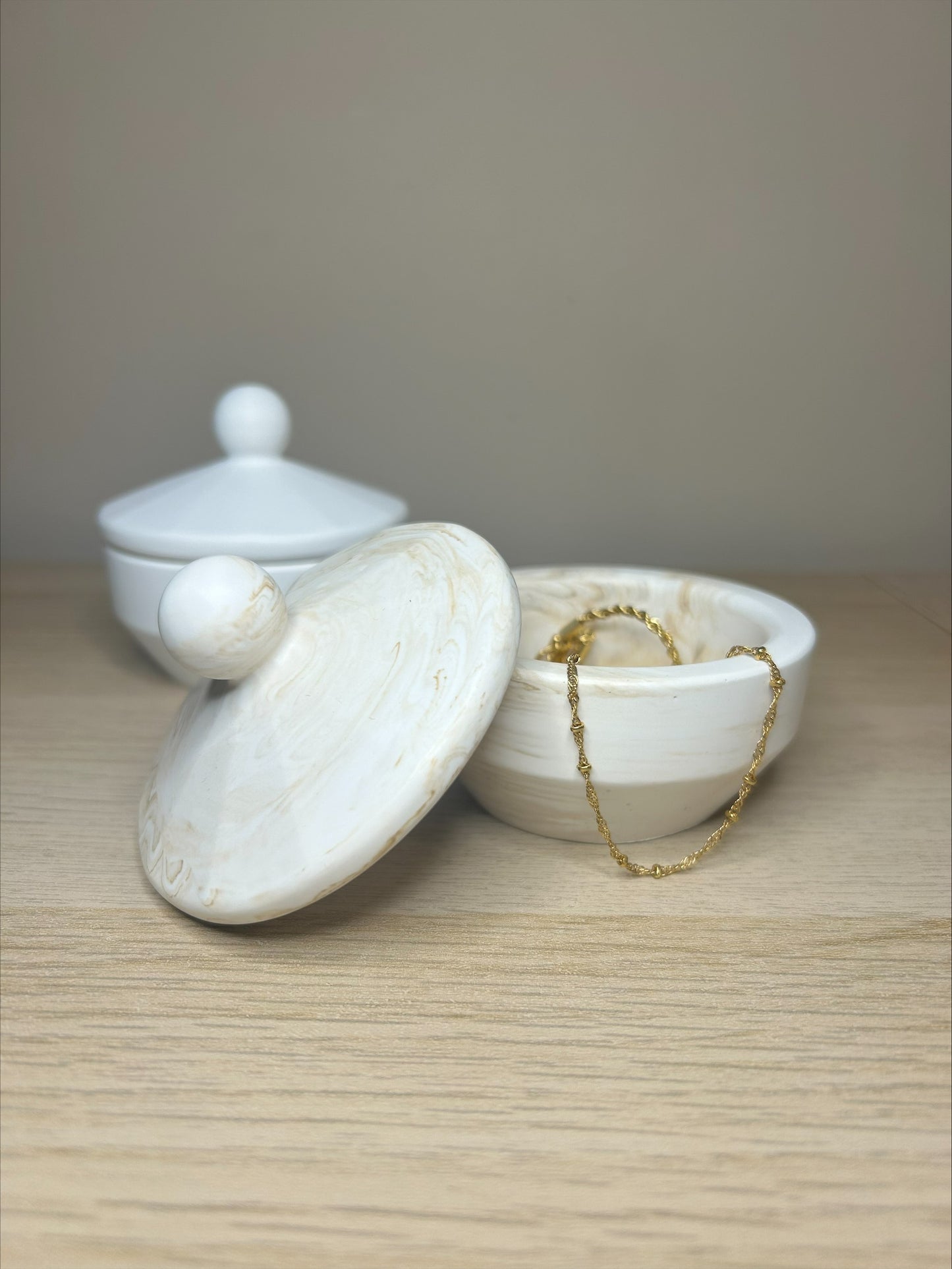 Handmade Home Accessories - a beige marble trinket pot thats open with a gold bracelet dangling over the edge