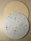 Handmade Home Accessories - a birds eye view photo of two terrazzo display plates overlapping each other, one is beige and one is grey.