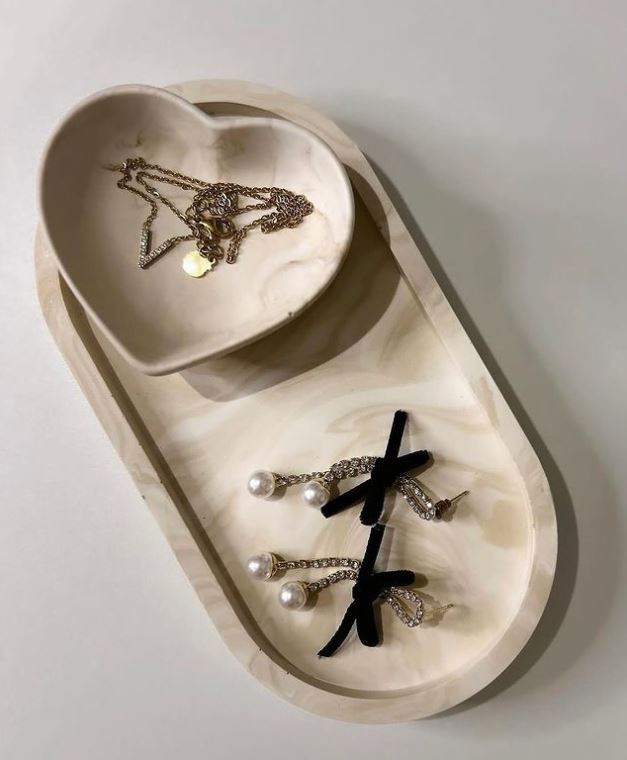 Handmade Home Accessories - A stylised shot of the beige marble tray and matching heart pot, displayed with earrings and a necklace.