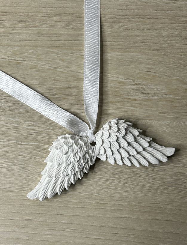 Handmade Home Accessories - a pair of angel wings on a white ribbon on a wooden surface